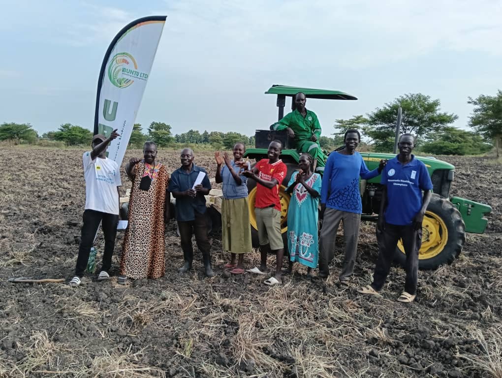 Ubuntu team and community members beside a tractor on prepared farmland